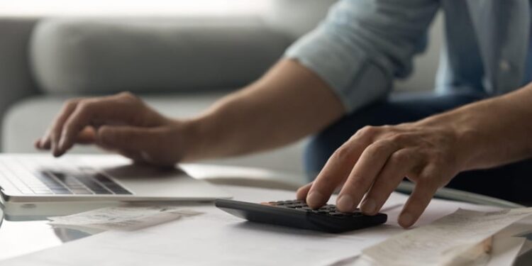 Man bookkeeper working with bills pay taxes online using laptop