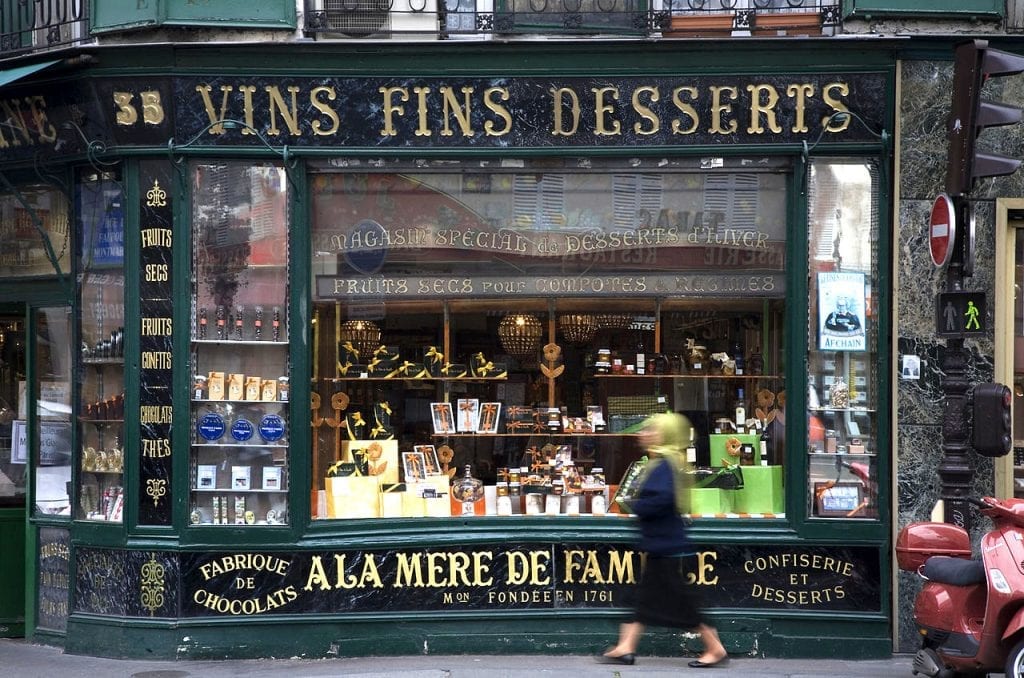 Woman walking past a wine and desserts shop