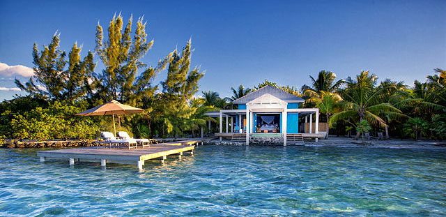an island home with a porch and a dock with loung chairs. cayo belize