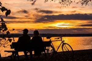 Couple sitting together on a bench watching the sunset, while enjoying the benefits of the Belize QRP Program.