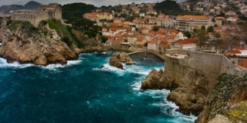 Orange roofed homes and blue ocean crashing against the rocky shores in the coast of Croatia