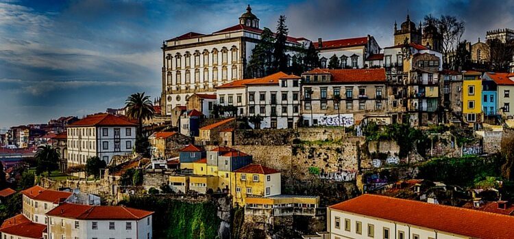 A hillside in Portugal with brightly colored buildings and a calm blue sky in the background