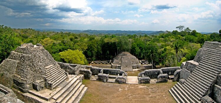 A view over the Cayo District of Belize, with large stone ruins and dense forest in the distance