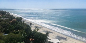 Blue skies and white and black sand beach in Coronado, Panama