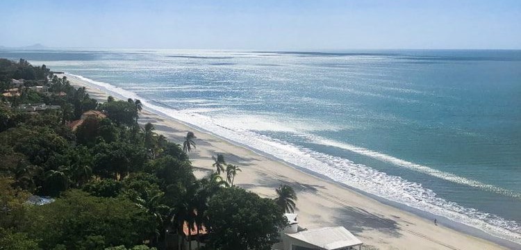 Blue skies and white and black sand beach in Coronado, Panama