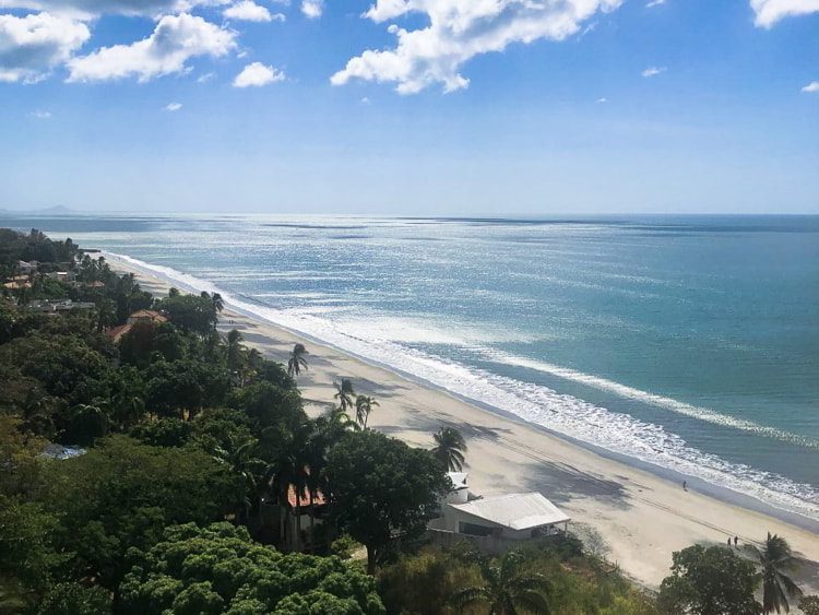 Blue skies and white and black sand beach in Coronado, Panama