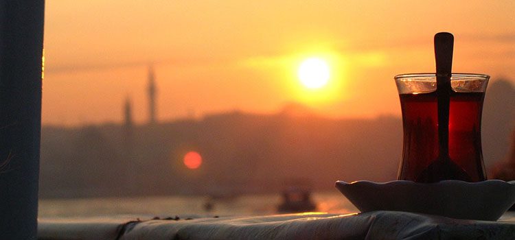 A Glass Of Turkish Tea with the Sunset in teh background