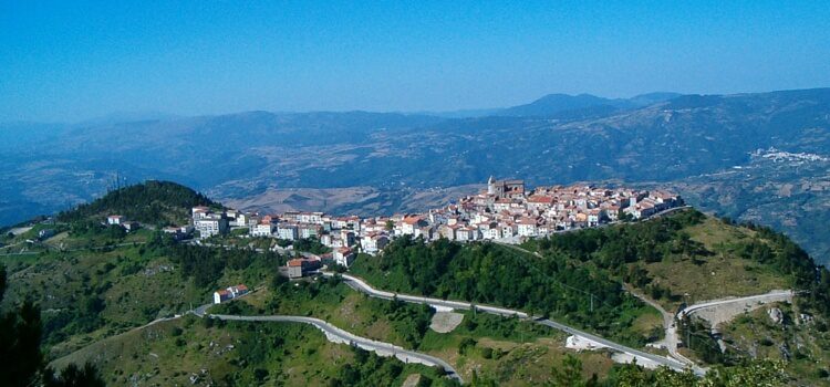 An aerial view of Abruzzo, Italy with a town on a hilltop and mountains in the distance