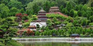 A hillside with a temple in China with water in front and