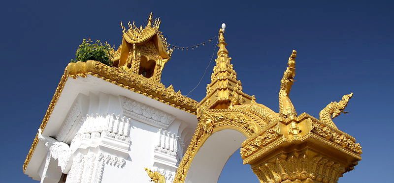 a gold roofed buddhist temply against a blue sky