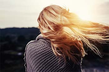 the back view of a blond woman's hair is flapping in the wind