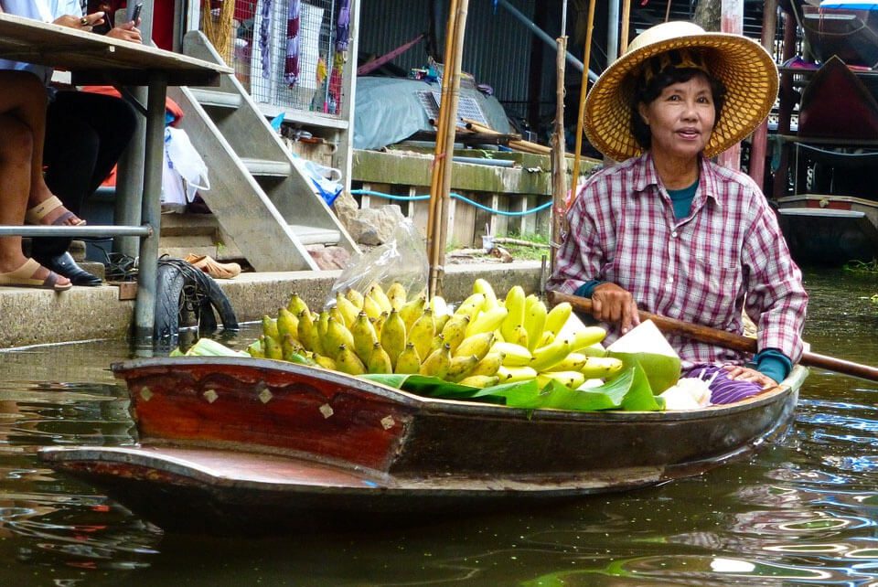 Thai woman floating on river in boat loaded with bananas
