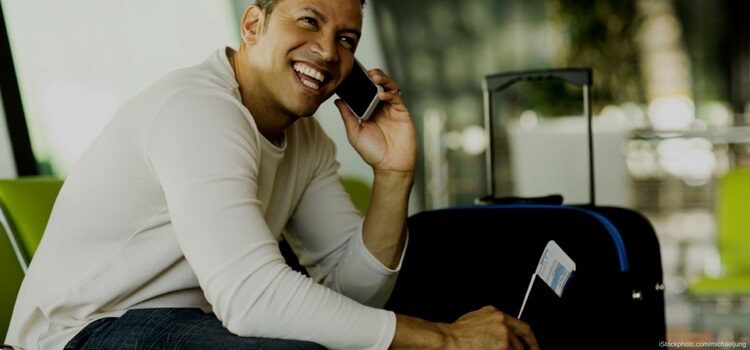 A man sitting at the airport talking on the phone waiting to board his plane and move to Uruguay.