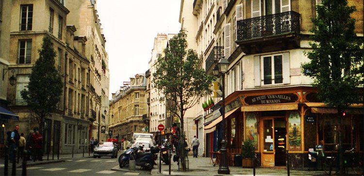 busy street corner in paris with people, cars and motorcycles