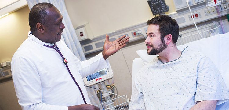 A doctor talks to a patient in a hospital room