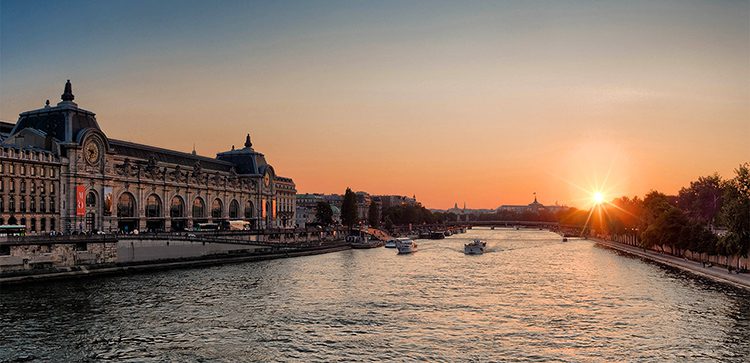 the sun setting in the distance over the Seine river