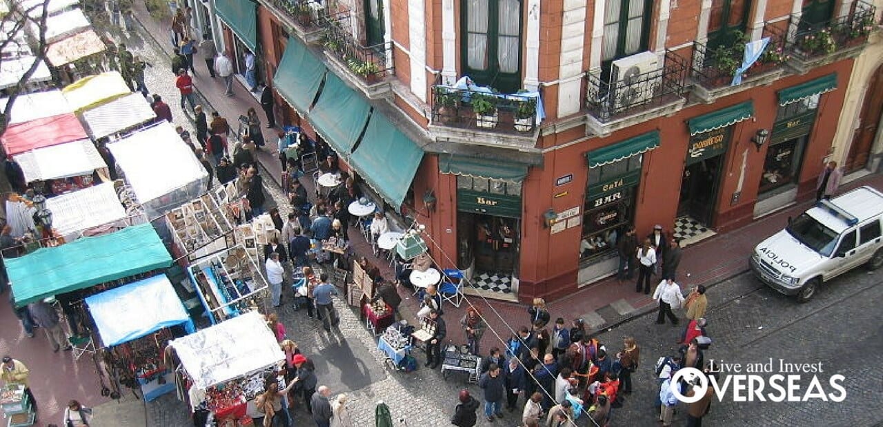 looking down on a street corner with outdoor stands selling a cariety of goods