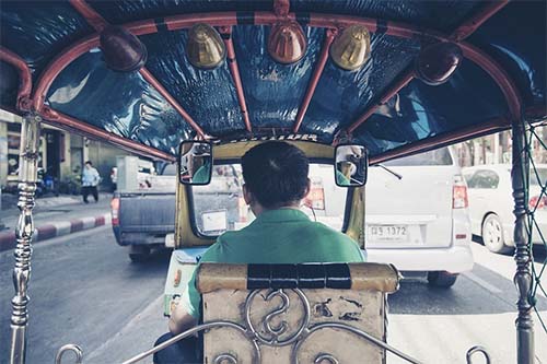 a tuk tuk driver as seen from the back seat of the tuk tuk