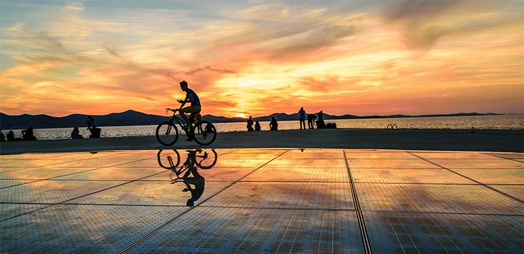 a silhouetted person on a bicycle at sunset