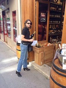 Kathleen holding a bottle of wine outside a wine shop