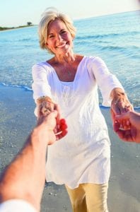 Happy senior woman holding hands with a man on the beach