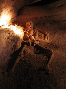 a skeleton splayed out on the floor of a mayan cave