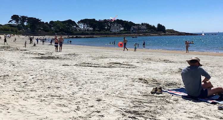 People enjoying a sunny day on a white sand beach in Brittany