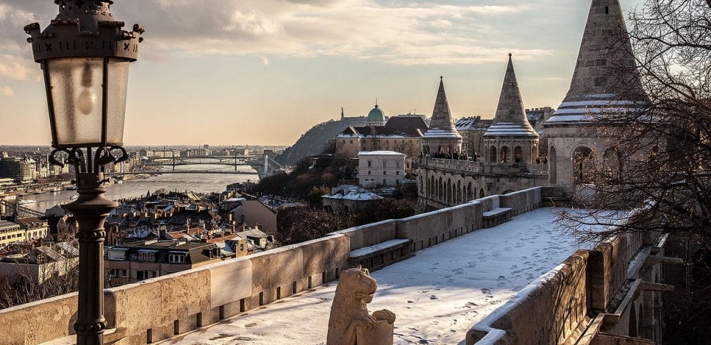 a snow covered bridge overlooking the beautiful Budapest architecture