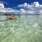 Wooden boats rowing away from an Indonesian beach