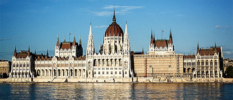 The very large parliament buildign by the Danube river glows in the light of the setting sun