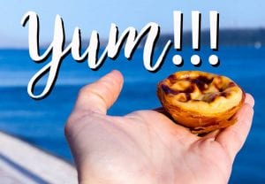 a hand holding up a little tart with the sea in the background
