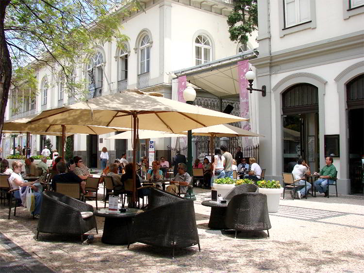 people eating at tables with umbrellas at an outdoor cafe in madeira