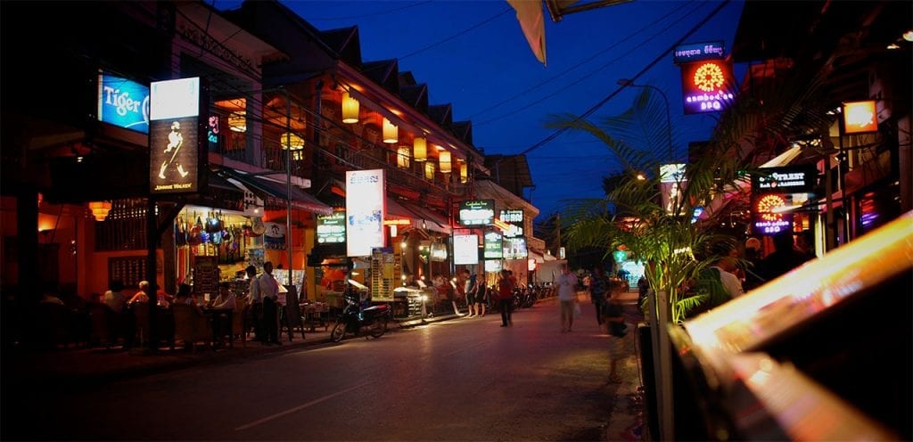 a siam reap street lined with shops lit up at night