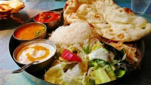 a plate of indian sauces, rice, salad and naan