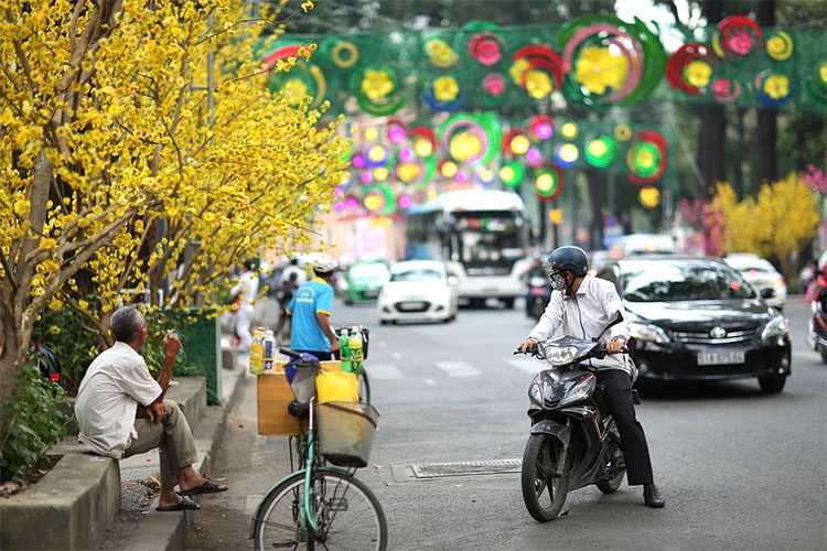 a busy street with moped, bikes, and cars