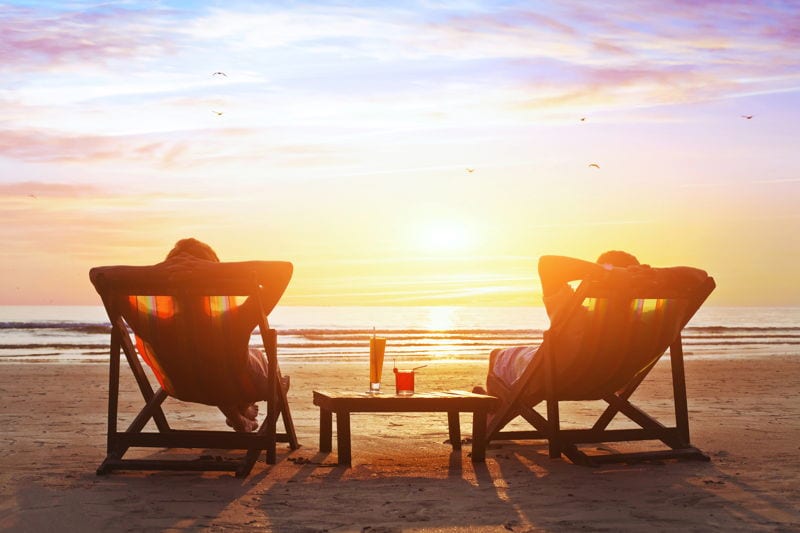 retired couple enjoying a sunset at the beach