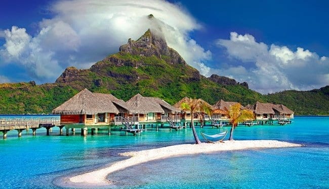 Bora Bora huts over the water with mountain in the background