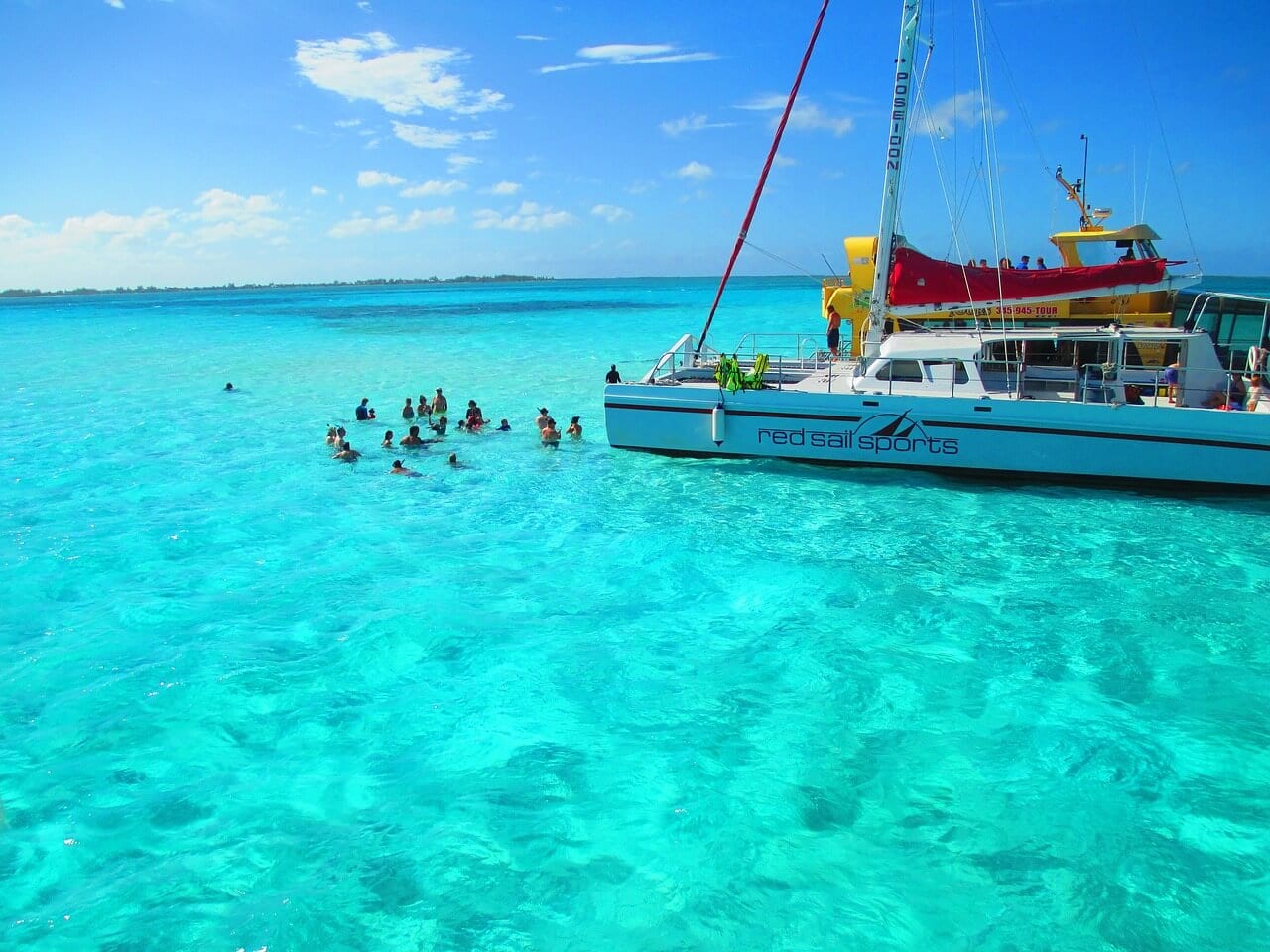 A boat and people sitting in the crystal clear blue water off the shores of the Cayman Islands