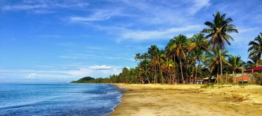 A calm and remote beachfront in Fiji, with palm trees swaying in the background.