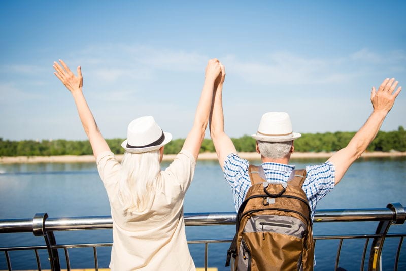 A happy retired couple travelling on a boat towards an island