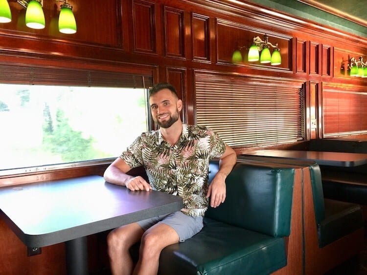 view from inside one of the quiet carriages in the panama canal railway. man in hawaiian shirt sitting on train bench