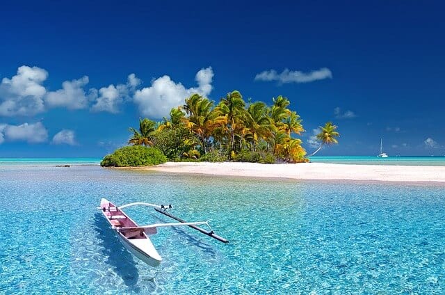 A white-sand beach on an island with a kayak and clear blue water.