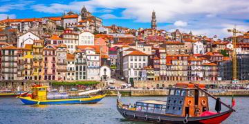 View of Porto Portugal, two colorful boats with the city behind them. taxes in portugal
