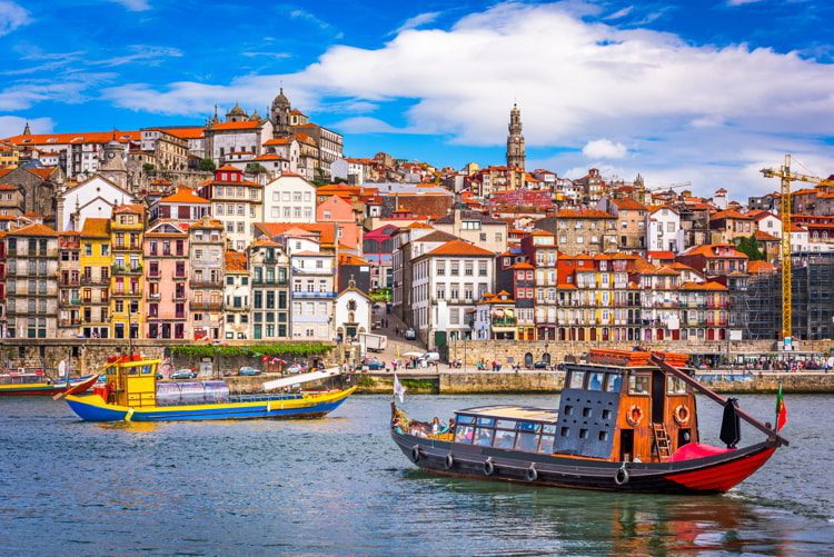 View of Porto Portugal, two colorful boats with the city behind them