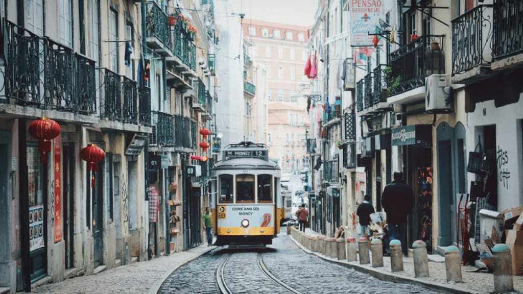 A vintage yellow tram climbs uphill along a street in lisbon, portugal