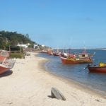 A white sand beach with red boats in Canelones, Uruguay