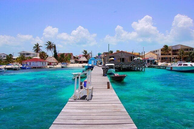 A near-white dock divides the light blue-green waters off the boast of Belize.