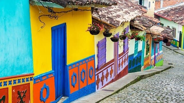 Brightly colored homes with flower baskets lining a cobblestone street in Colombia.