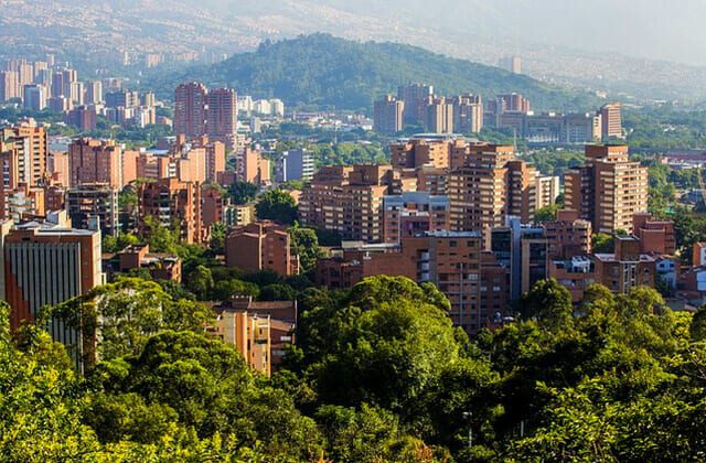 View of Medellin with lush green trees scattered between brick buildings.