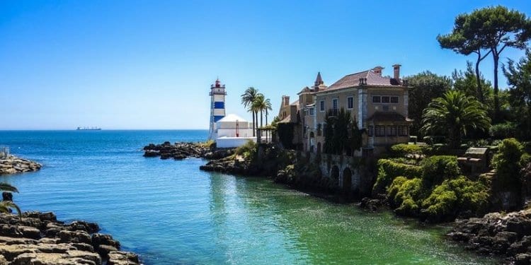 lighthouse in cascais portugal under clear blue skies with clear green waters